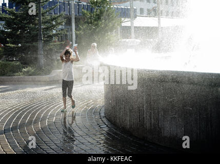 La fillette de sept ans est dans une éclaboussure de runing fontaine eau. Banque D'Images