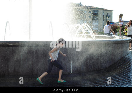 Ivano Frankivsk, Ukraine, le 18 juin 2017. La petite fille de 7 ans est en fonctionnement une éclaboussure de l'eau de la fontaine. Banque D'Images