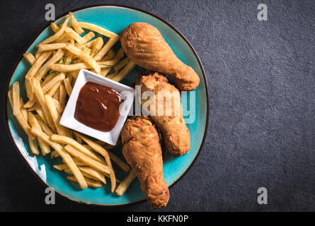 Frites, poulet frit jambes sur fond sombre avec l'espace blanc Banque D'Images