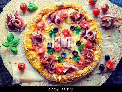 Pizza gastronomique maison de prosciutto et de légumes d'en haut sur la table en bois Banque D'Images