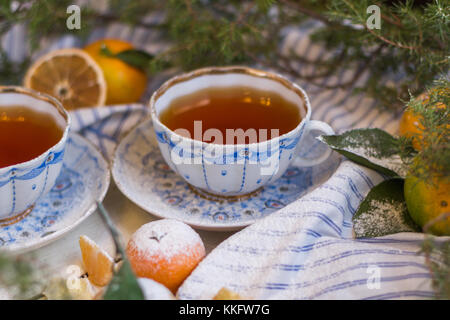 Mandarin couverts avec du sucre en poudre. Noël encore la vie. le mandarin et tasses de thé sur un fond de bois blanc. Banque D'Images