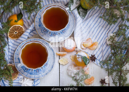 Plateau dans de belles tasses en porcelaine. Nouvel an matin. les mandarines et les tasses de thé sur un fond de bois blanc. vue d'en haut. Banque D'Images