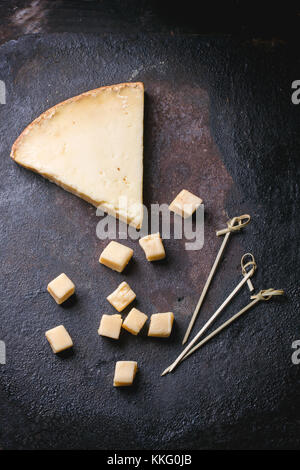 Gros morceau et de petits cubes de fromage belge sur fond noir. vue d'en haut. Banque D'Images