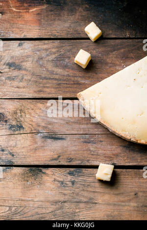 Gros morceau et de petits cubes de fromage belge sur fond de bois. vue d'en haut. Banque D'Images