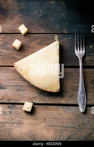 Gros morceau et de petits cubes de fromage belge avec vintage fourchette sur fond de bois. vue d'en haut. Banque D'Images