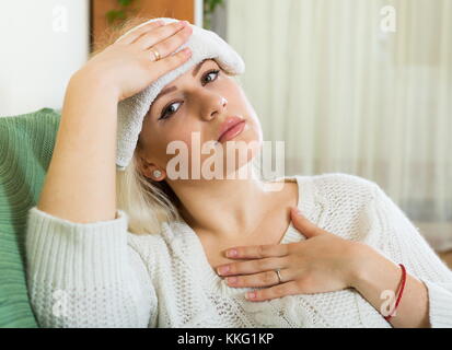 Femme avec d'énormes migraines holding serviette mouillée sur la tête Banque D'Images