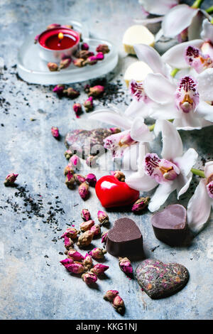 Bonbons de chocolat en forme de coeur avec un plateau sec et les orchidées roses pour la Saint Valentin. Banque D'Images