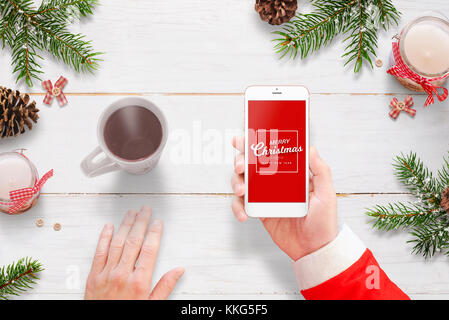 Père Noël joyeux noël envoyer message avec téléphone mobile. Le thé chaud, et à côté de décoration de Noël. Banque D'Images