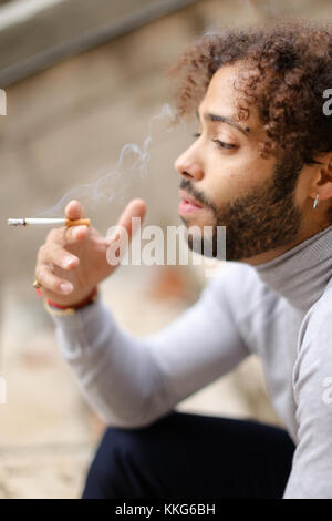 Jeune fumeur mulâtre de la toux sur les mesures avec la cigarette. Banque D'Images