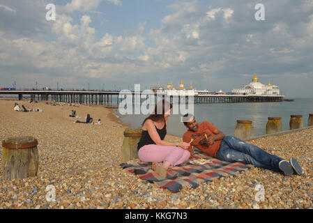 Un couple eating chips sur la plage d'Eastbourne, East Sussex, England, UK Banque D'Images
