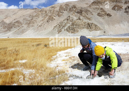 La mère et le fils de toucher de l'eau chaude d'un geyser dans la zone géothermique de Puga, le Ladakh, le Jammu-et-Cachemire, en Inde. Banque D'Images