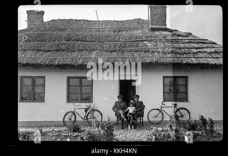 Cette image de 2014 montre deux soldats assis avec un enfant et des vélos devant une maison en Roumanie. Il reflète une scène quotidienne avec une présence militaire. Banque D'Images