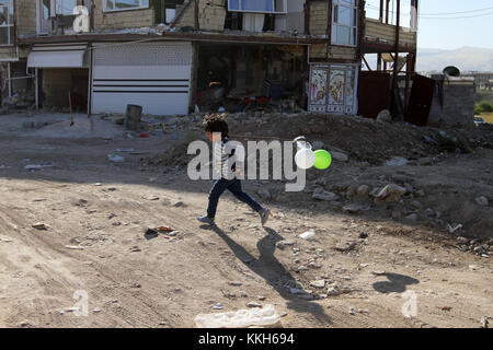 17 novembre 2017 - sarpol-e zahab, Kermanshah, Iran - un garçon rescapé du tremblement de terre joue avec ses ballons en face de bâtiments endommagés. crédit : saghar amirazimi/zuma/Alamy fil live news Banque D'Images