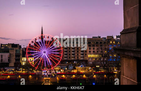 Edinburgh, Ecosse, Royaume-Uni, le 30 novembre 2017. La célébration de Noël Marché de Noël d'Édimbourg et de manèges forains, avec l'avant 1 grande roue dominant la vue sur les jardins de Princes Street. Le centre-ville est éclairée avec des lumières colorées magnifique avec un coucher de soleil rose sur une soirée d'hiver Banque D'Images