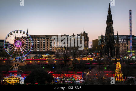 Edinburgh, Ecosse, Royaume-Uni, le 30 novembre 2017. La célébration de Noël Marché de Noël d'Édimbourg et de manèges forains, avec l'avant 1 grande roue dominant la vue sur les jardins de Princes Street, et un pêle-mêle. Le centre-ville est éclairée avec des lumières colorées magnifique au coucher du soleil sur une soirée d'hiver Banque D'Images