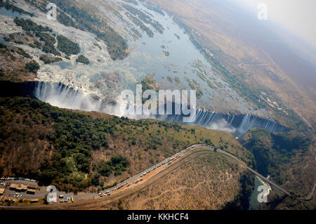 Une vue des chutes Victoria et du large cours du fleuve Zambèze face à la Zambie, avec des camions sur une route au premier plan attendant d'entrer en Zambie, photo le 30.07.2015. Les chutes Victoria sont les grandes cascades du Zambèze à la frontière entre le Zimbabwe et la Zambie. Les chutes ont été découvertes par le missionnaire écossais David Livingstone, qui les a nommées en l'honneur de la reine Victoria de Grande-Bretagne. Les chutes Victoria sont classées au patrimoine mondial de l'UNESCO depuis 1989. L'eau tombe jusqu'à 110 mètres sur une largeur de plus de 1 700 mètres. Photo : Matthias Tödt | utilisation dans le monde entier Banque D'Images