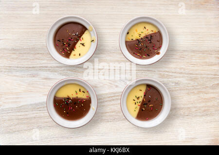 Vanille et chocolat dessert crémeux avec orned bonbons multicolores sur fond de table en bois Banque D'Images