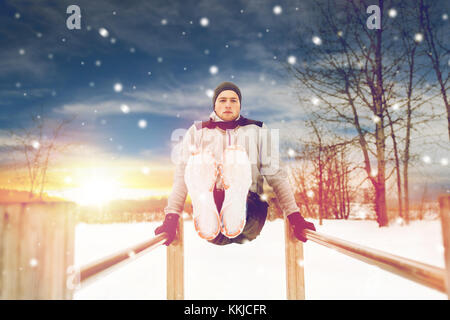 Jeune homme exerçant sur les barres parallèles en hiver Banque D'Images