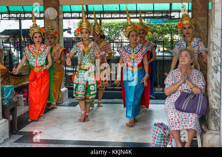 Bangkok, Thaïlande. Sanctuaire d'Erawan. Danseurs thaïlandais de la danse comme une bénédiction pour le donateur qui est assis en fauteuil. Banque D'Images