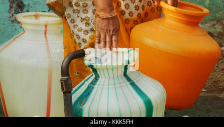 L'eau des indiens à tuyau remplissage d'un pot d'eau en plastique. femme transporter de l'eau pot. Banque D'Images