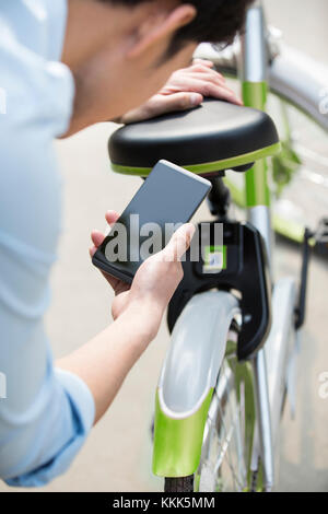 Les jeunes Chinois de la numérisation d'un QR code pour débloquer un vélo partager Banque D'Images