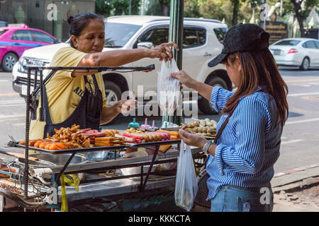 Bangkok, Thaïlande. Street Food Vendor offrant des brochettes, hot-dogs, viandes grillées. Banque D'Images