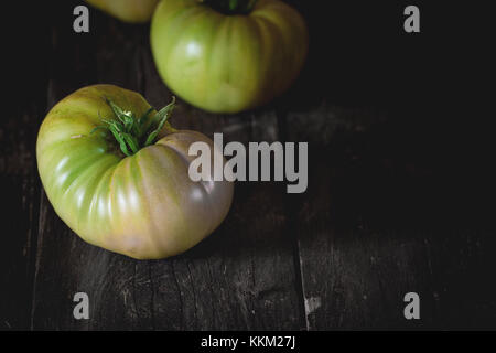 Gros fruit vert vert tomates raf plus vieille table en bois sombre de style rustique.. la lumière naturelle du jour. avec copie espace à droite Banque D'Images