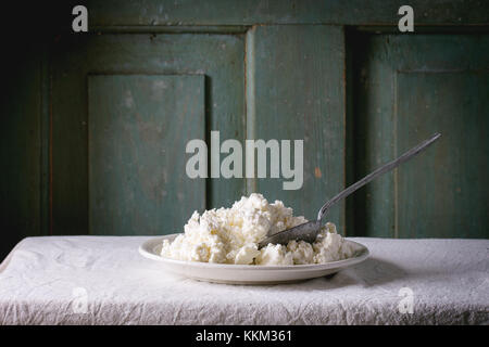 Assiette de fromage fait maison sur nappe blanche avec fond en bois foncé turquoise. atmosphère rustique. Banque D'Images