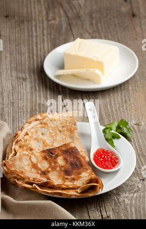 Assiette de crêpes avec du caviar rouge et beurre frais servi sur la vieille table en bois Banque D'Images