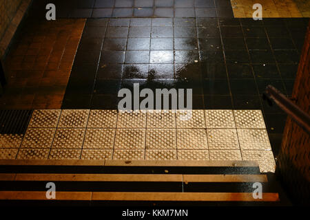 Les étapes d'un sombre tunnel de la station avec les flaques et les murs humides. Banque D'Images