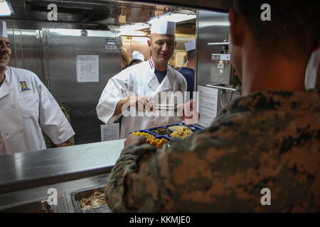 La commande de la Marine américaine Master Chief Benjamin Hodges, directeur principal de la station de transport amphibie USS New York (LPD 21) sert de la nourriture à un milieu marin avec la 26e MEU pendant un jour de l'action de grâce le dîner dans l'océan Atlantique, le 23 novembre 2017. L'Iwo Jima Groupe amphibie et 26e MEU équipe a célébré Thanksgiving en mer au cours de l'exercice de l'unité de formation composite combinée. (U.S. Marine Corps photo par le Cpl. Juan A. Soto-Delgado) Banque D'Images