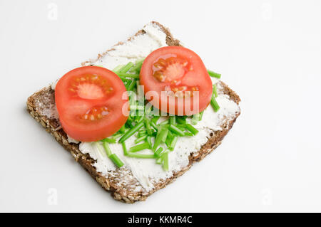 High angle view sur une tranche de pain avec du fromage à la crème, deux tranches de tomate et la ciboulette sur fond blanc. Banque D'Images