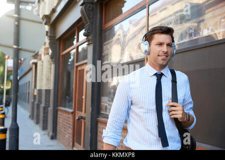 Businessman Wearing des écouteurs sans fil au travail à pied Banque D'Images