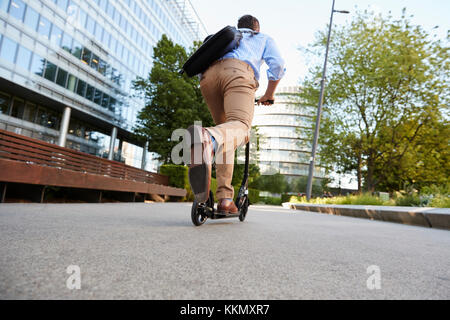 Jeune homme d'affaires pour se rendre à son travail par l'intermédiaire de ville en scooter Banque D'Images