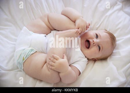 Coup de frais généraux de Happy Baby garçon couché sur le lit des parents Banque D'Images