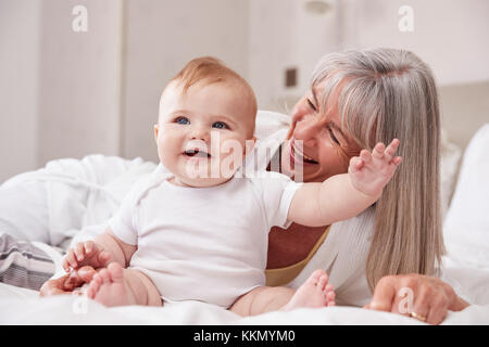Grand-mère au lit à la maison pour s'occuper de bébé petit-fils Banque D'Images