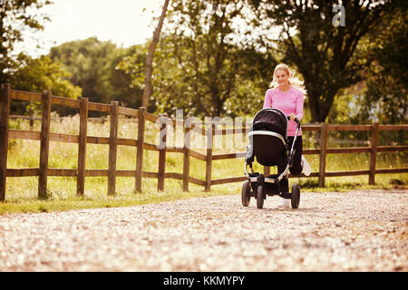 Mère exerçant en exécutant tout en appuyant Baby Buggy Banque D'Images