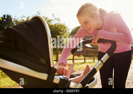 Mère exerçant en exécutant tout en appuyant Baby Buggy Banque D'Images