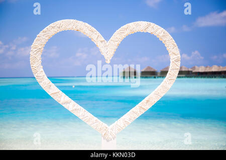 Coeur à prendre des photos de couples en lune de miel dans la plage aux Maldives avec un contexte tropical avec bungalows sur l'eau. C'est une belle journée ensoleillée Banque D'Images