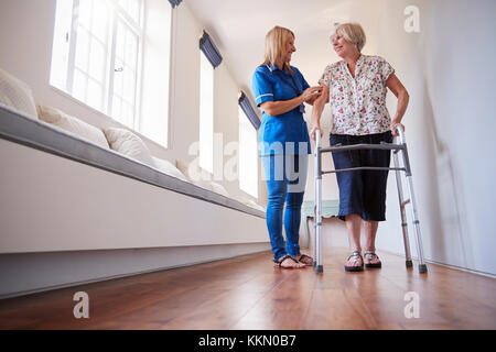 Nurse helping senior woman utiliser un déambulateur, pleine longueur Banque D'Images