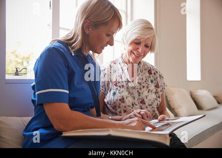 Senior woman looking at album photo avec infirmière Banque D'Images