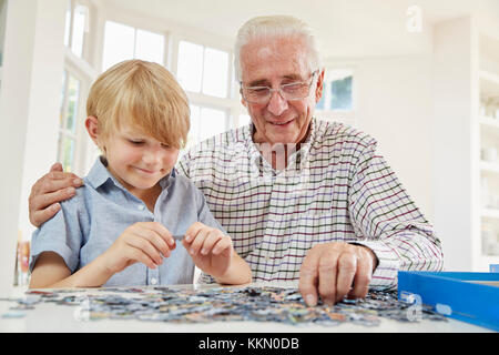 Man et petit-fils de faire un puzzle à la maison Banque D'Images