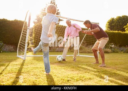 Trois générations d'une famille jouant au football Banque D'Images