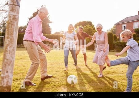 Multi generation family playing football dans le jardin Banque D'Images