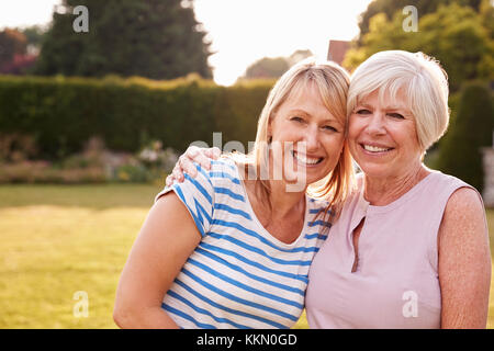 Senior woman and adult daughter embracing in garden Banque D'Images