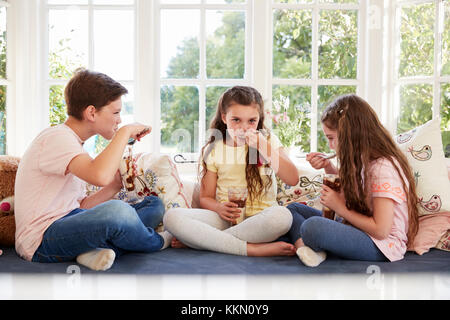 Des enfants assis sur le siège côté fenêtre Eating Ice Cream Sundae Banque D'Images