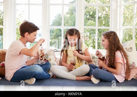 Des enfants assis sur le siège côté fenêtre Eating Ice Cream Sundae Banque D'Images