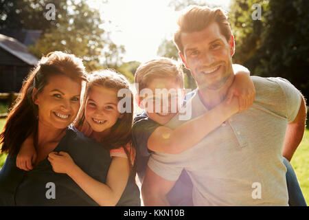 Portrait d'enfants Les parents qui s'y greffent en jardin Banque D'Images