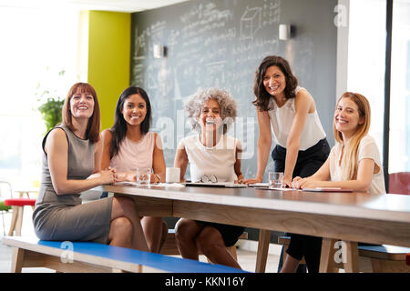 Heureux collègues femmes lors d'une réunion de travail à l'appareil photo en souriant Banque D'Images