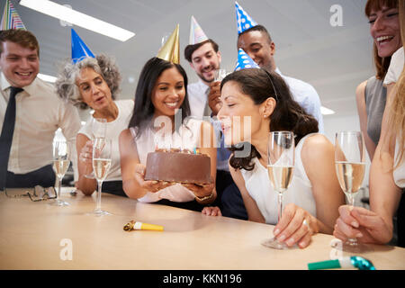 Femme souffle les bougies sur le gâteau d'anniversaire in office Banque D'Images